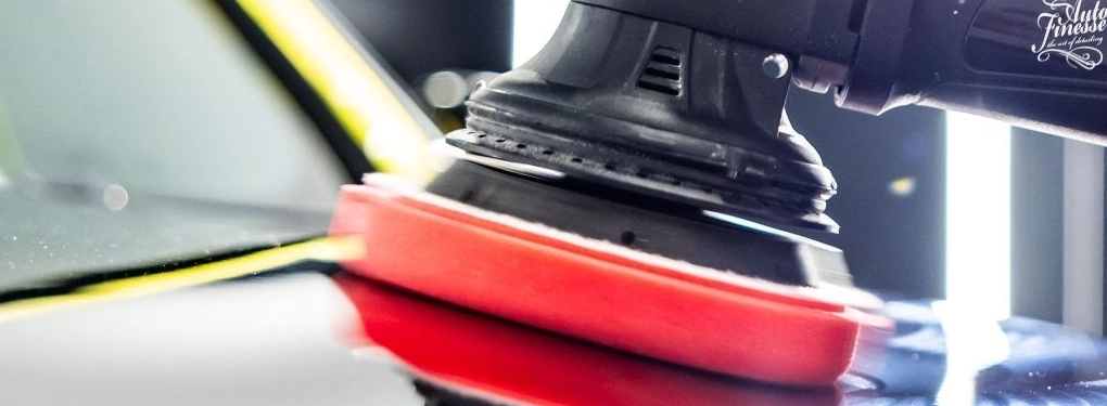Dual action car polisher in use on black car bonnet
